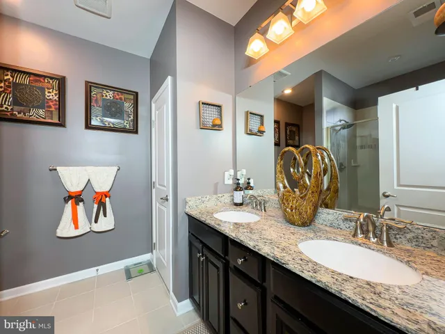 a bathroom with double vanity sinks a vanity and a large mirror