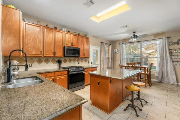 a kitchen with stainless steel appliances granite countertop sink stove top oven and cabinets