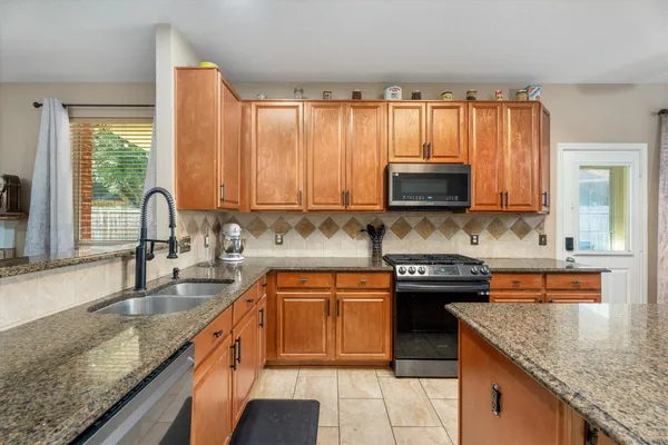 a kitchen with granite countertop a stove a sink and a microwave