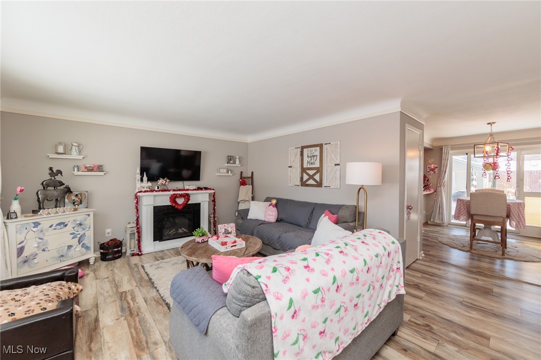 Living room featuring hardwood / wood-style floors, crown molding, and a notable chandelier