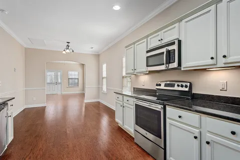 a kitchen with stainless steel appliances granite countertop a stove top oven a sink dishwasher and cabinets with wooden floor