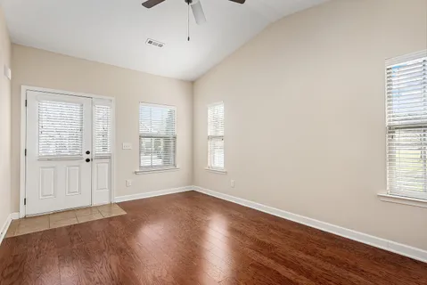 a view of an empty room with wooden floor and a window