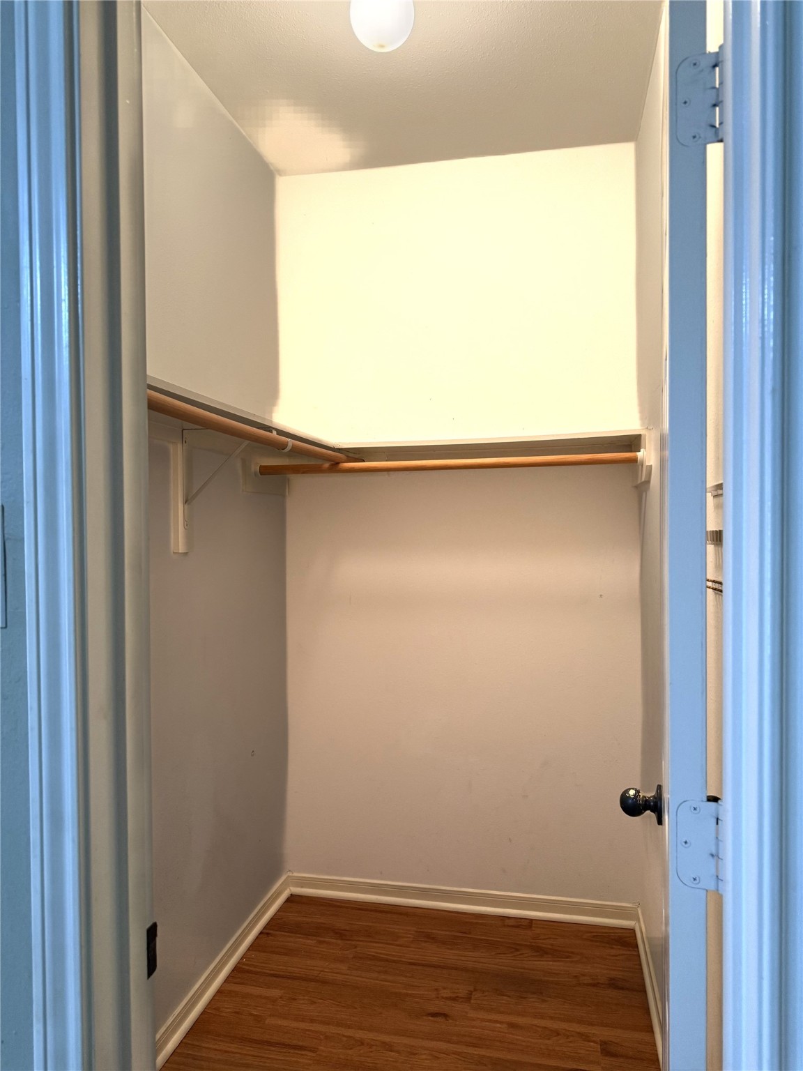 915 Saginaw Bay Court Spring, TX 77373 - Photo 12 of 15 This is a spacious walk-in closet with vinyl wooden flooring, white walls, and a ceiling light. It includes hanging rods and shelving for ample storage.