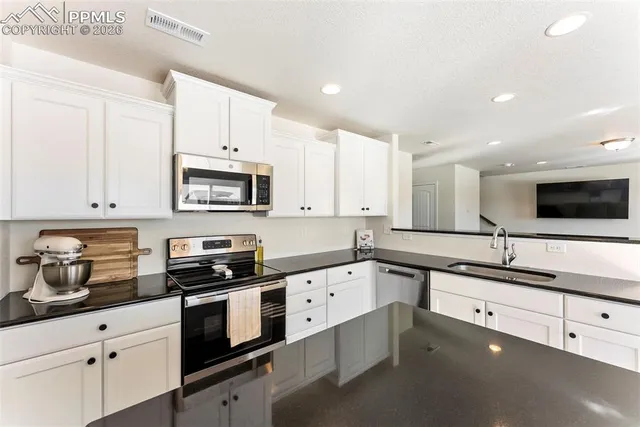 a kitchen with granite countertop white cabinets and white appliances