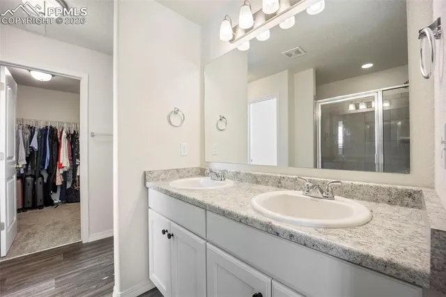 a bathroom with a granite countertop double vanity sink and a mirror