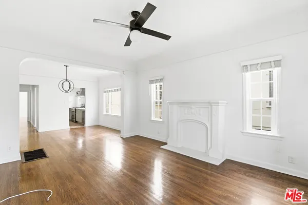 a view of a big room with wooden floor a ceiling fan and windows