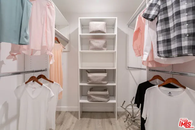 a view of walk in closet with clothes and shoes