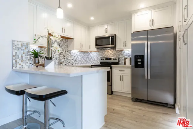 a kitchen with stainless steel appliances a refrigerator a stove a sink cabinets and a dining table