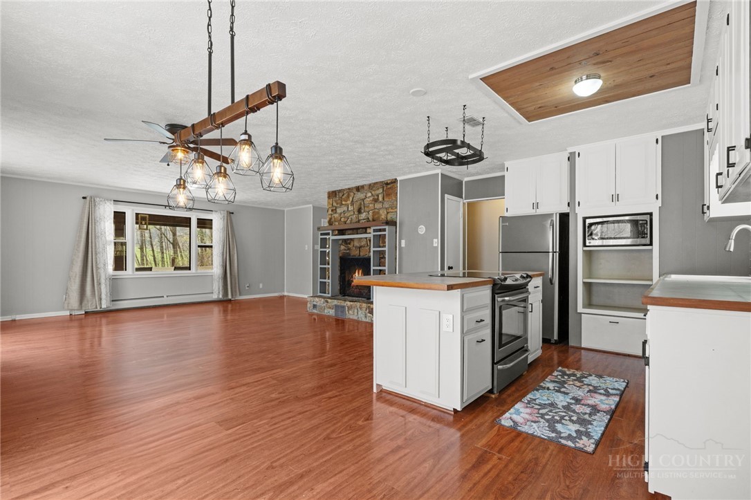 2345 Watauga River Road Sugar Grove, NC 28679 - Photo 7 of 50 a kitchen with stainless steel appliances kitchen island granite countertop a refrigerator a stove top oven a sink dishwasher and a dining table with wooden floor