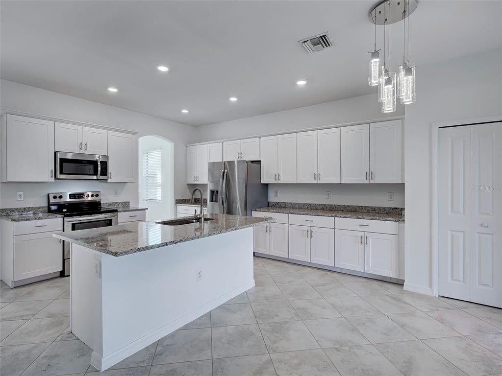 1824 East Isles Rd Port Port Charlotte, FL 33953 - Photo 24 of 80 a large kitchen with granite countertop a sink and dishwasher a stove top oven with white cabinets
