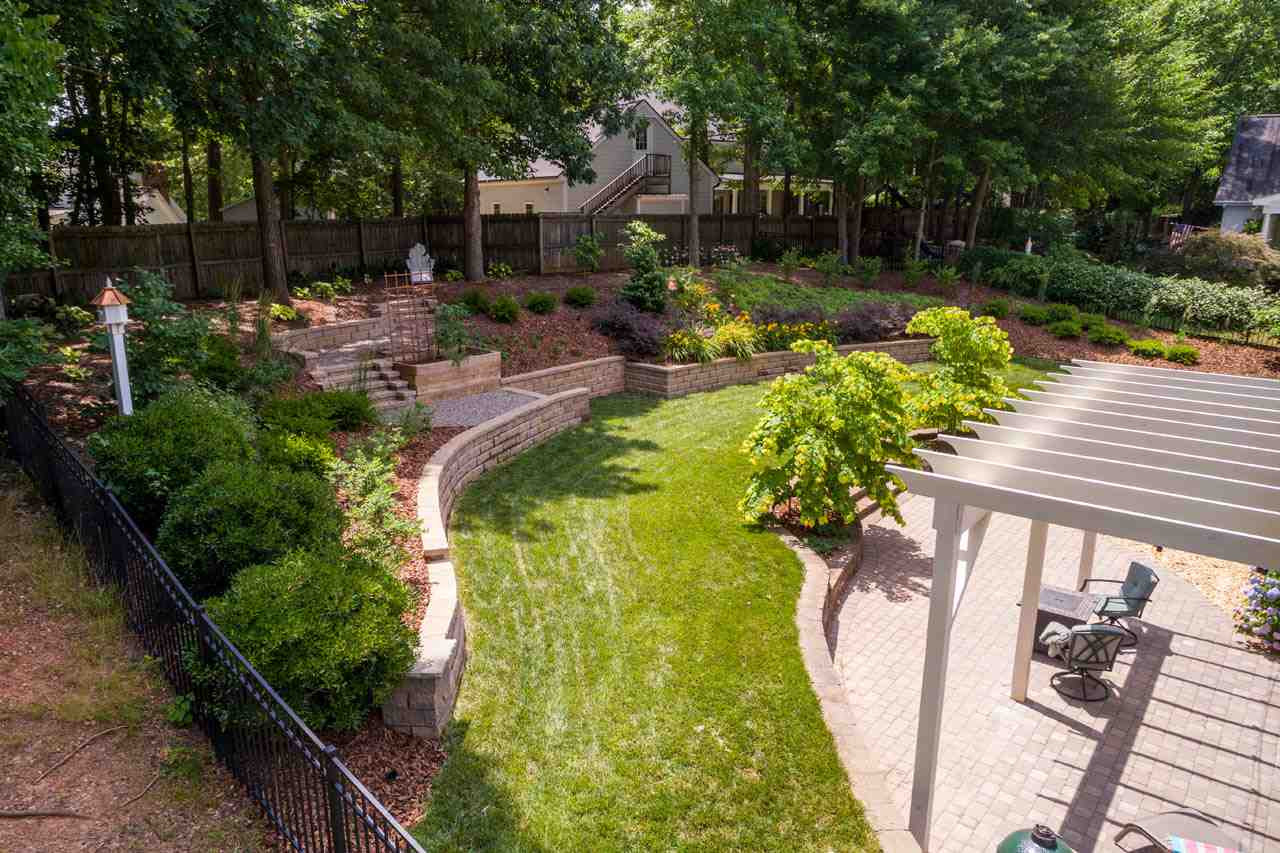 1716 Stannard Trail Raleigh, NC 27612 - Photo 27 of 30 Professionally designed backyard oasis with large grassy area, stonewalls, and steps to natural area. One area off the patio has been prepared for a playset. Professoinally designed backyard with Exquisite Landscaping