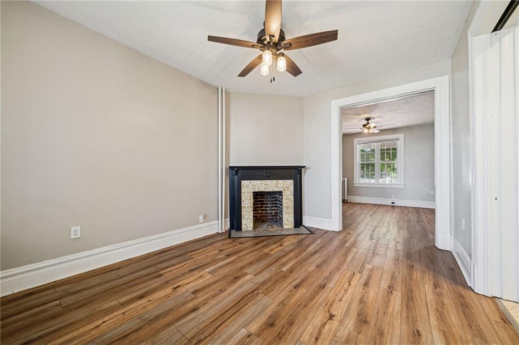 147 Hamilton Avenue Vandergrift, PA 15690 - Photo 13 of 32 an empty room with wooden floor a ceiling fan and a fireplace
