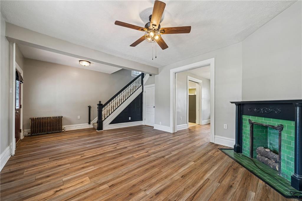 147 Hamilton Avenue Vandergrift, PA 15690 - Photo 9 of 32 a view of an empty room with wooden floor a ceiling fan and a fireplace