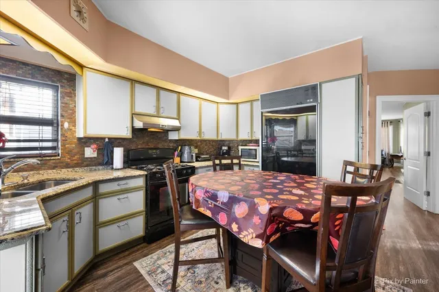 a kitchen with stainless steel appliances granite countertop a stove a sink dishwasher a dining table and chairs with wooden floor