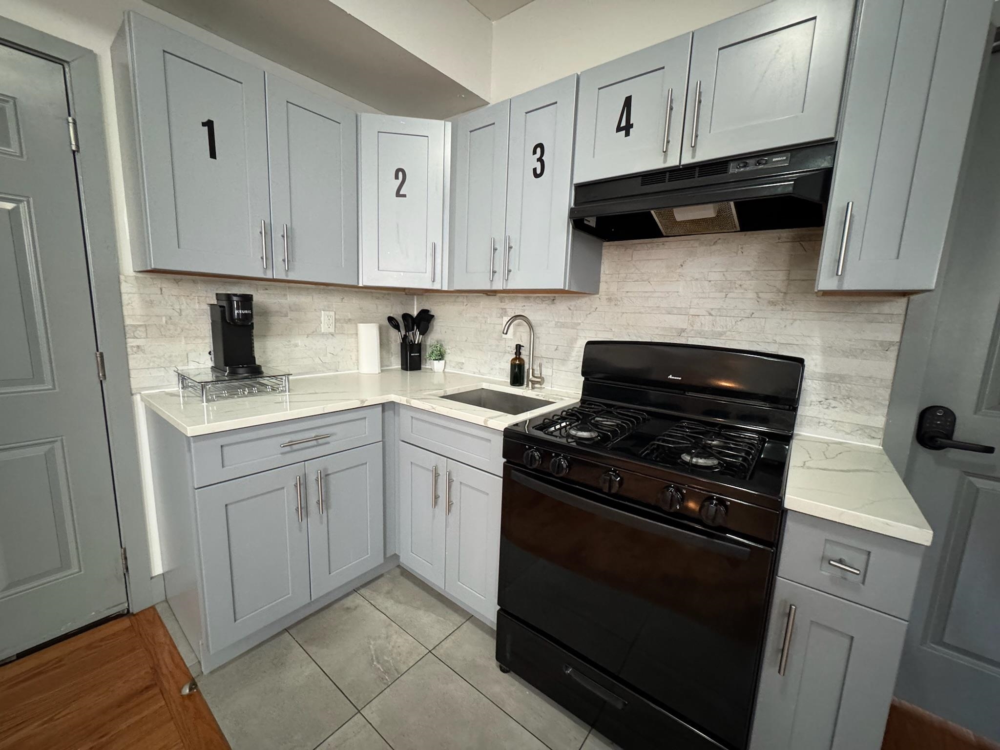 157 Bidwell Avenue, Unit 2 Jersey City, NJ 07305 - Photo 4 of 34 a kitchen with white cabinets a stove top oven and sink