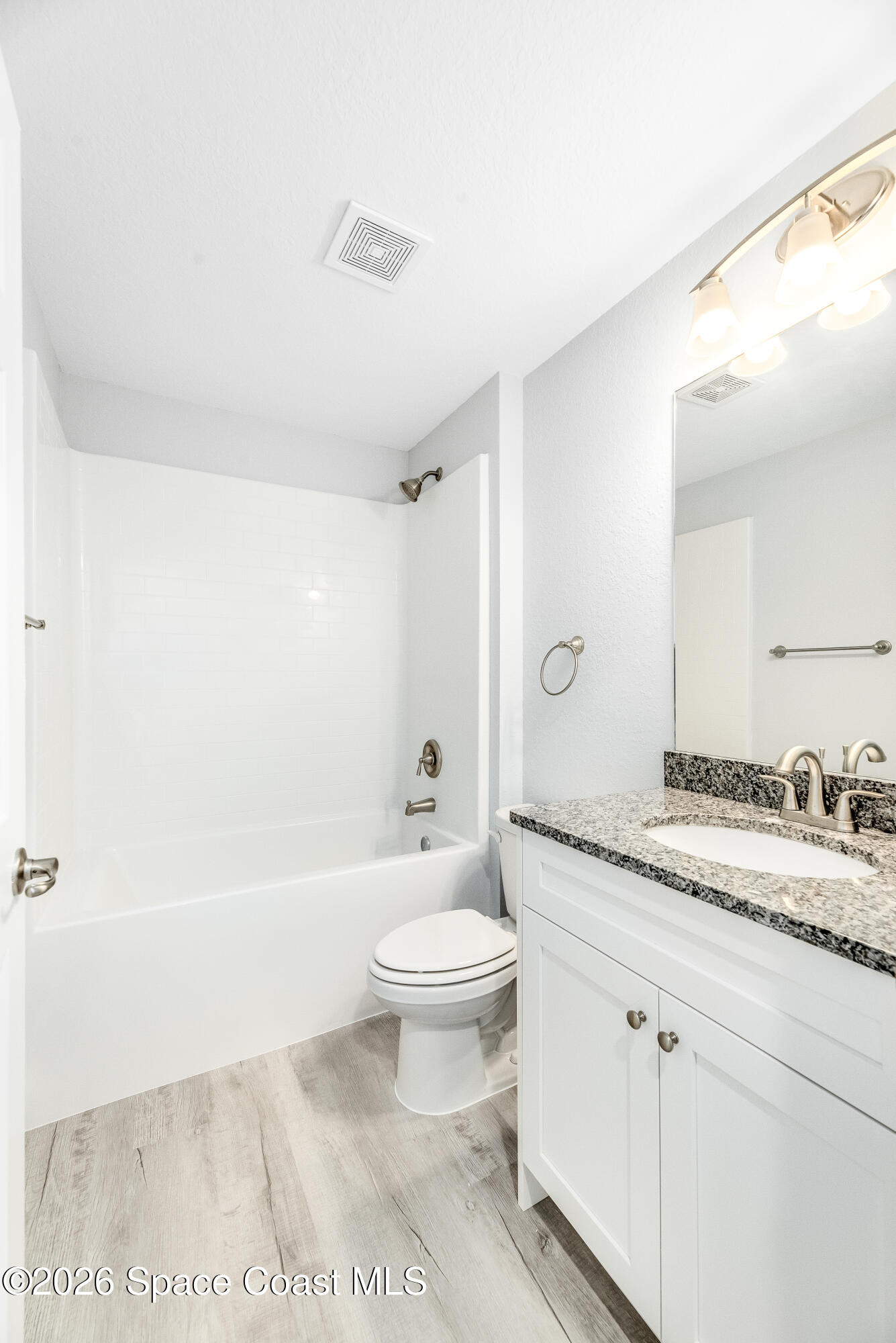 2977 Fig Road Southeast Palm Bay, FL 32909 - Photo 32 of 38 a bathroom with a granite countertop sink a toilet a mirror and bathtub