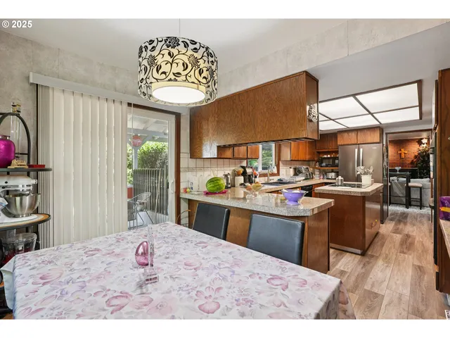 a kitchen with stainless steel appliances kitchen island granite countertop a sink dishwasher with a dining table and chair with wooden floor