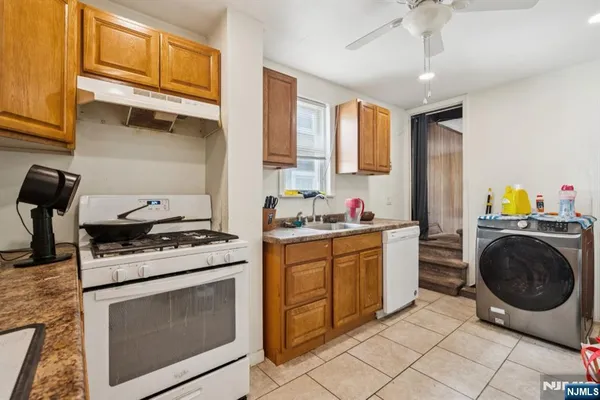 a kitchen with granite countertop a sink a stove top oven and cabinets