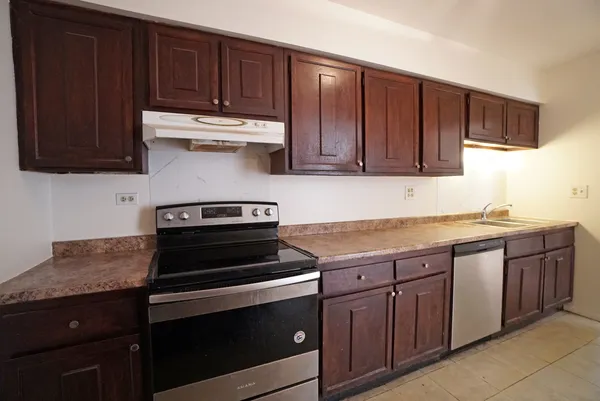 a kitchen with granite countertop wooden cabinets and a stove top oven