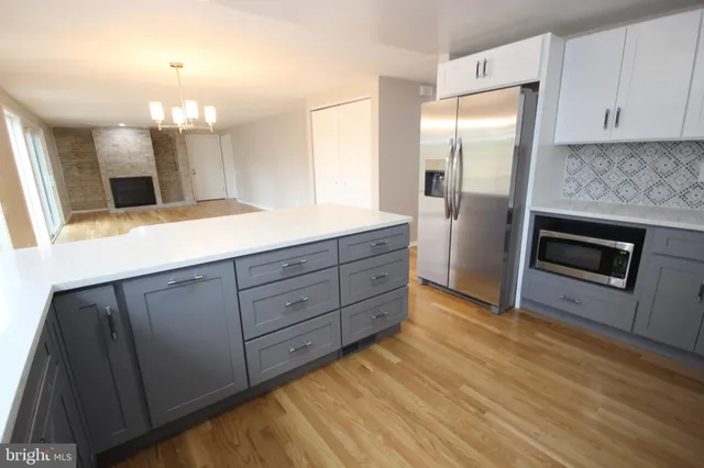 an empty room with wooden floor fireplace and windows