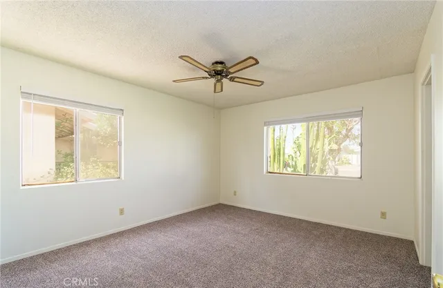 an empty room with windows and a ceiling fan