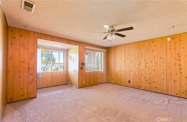 an empty room with chandelier fan and windows