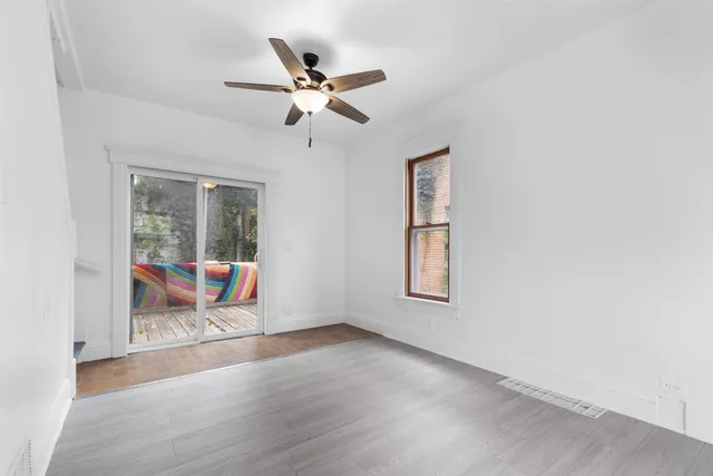 an empty room with wooden floor fan and windows