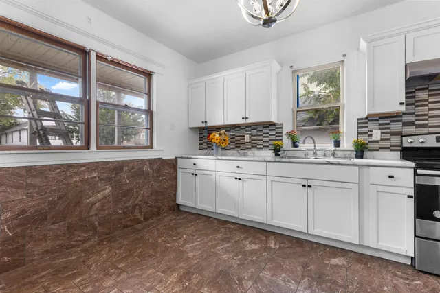 a kitchen with white cabinets and window