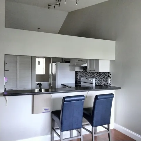 a kitchen with stainless steel appliances a sink a stove a refrigerator white cabinets and wooden floor