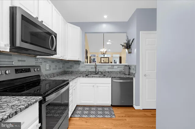 a kitchen with granite countertop a sink stainless steel appliances and white cabinets