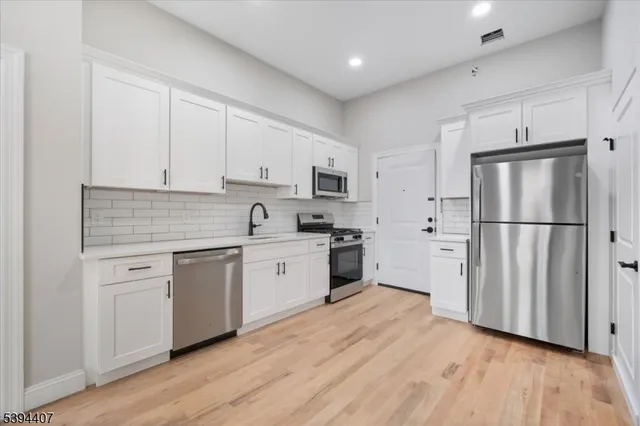 a kitchen with granite countertop white cabinets and stainless steel appliances