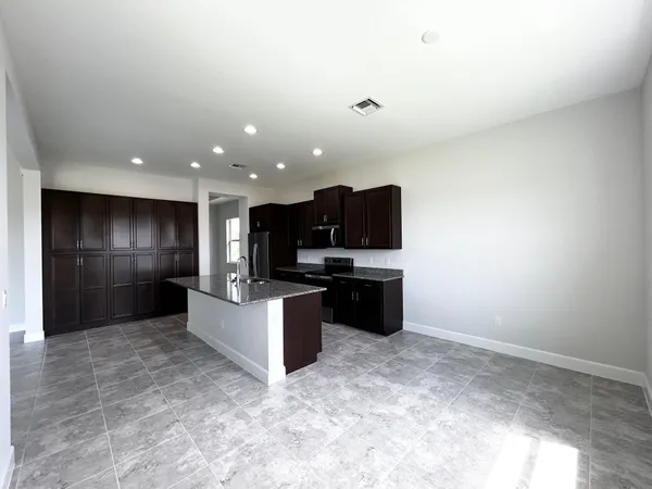 a view of kitchen with stainless steel appliances kitchen island sink refrigerator and microwave