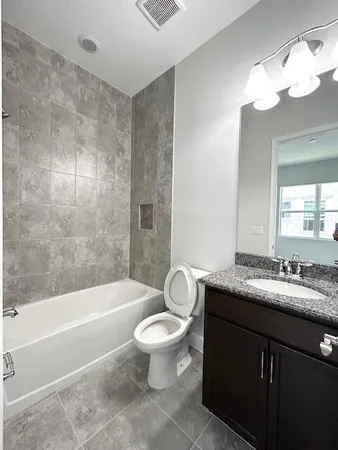 a bathroom with a granite countertop toilet a sink and a bathtub