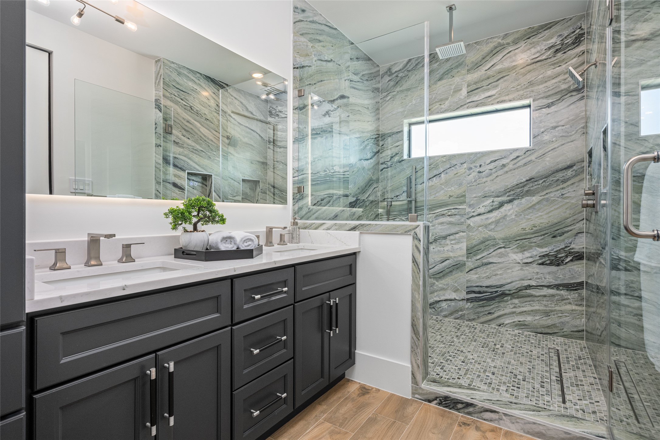 623 Rolling Oaks Stafford, TX 77477 - Photo 41 of 50 The shower suite boasts three heads—rainfall, wall-mounted, and handheld—surrounded by porcelain tile to the ceiling and framed by a bright window