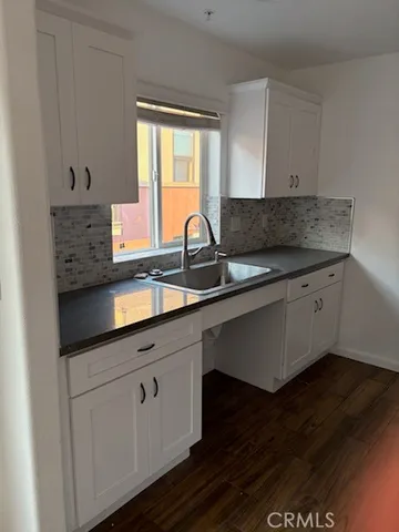 a kitchen with granite countertop a sink cabinets and wooden floor
