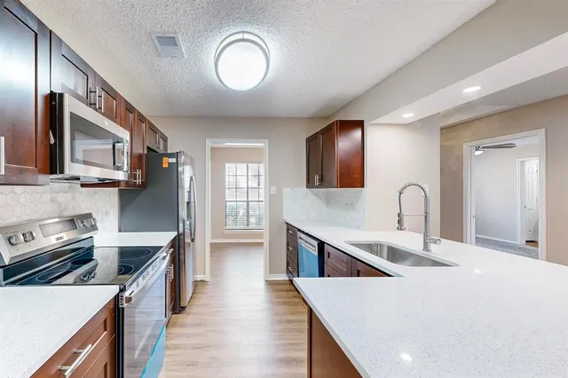 a kitchen with stainless steel appliances a stove microwave and sink