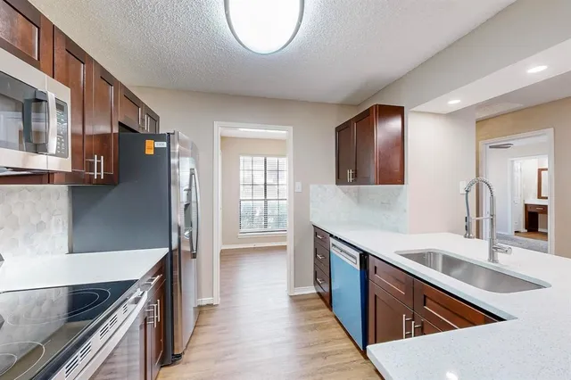 a large kitchen with stainless steel appliances granite countertop a sink and a stove top oven