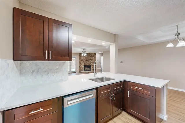 a kitchen with stainless steel appliances granite countertop a sink a stove top oven and wooden floor