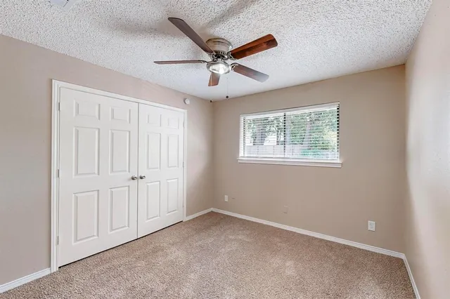 an empty room with a window and a fan