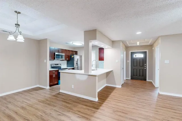 a view of kitchen with stainless steel appliances granite countertop refrigerator oven a sink dishwasher and white cabinets with wooden floor