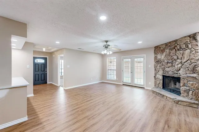 an empty room with wooden floor fireplace and windows