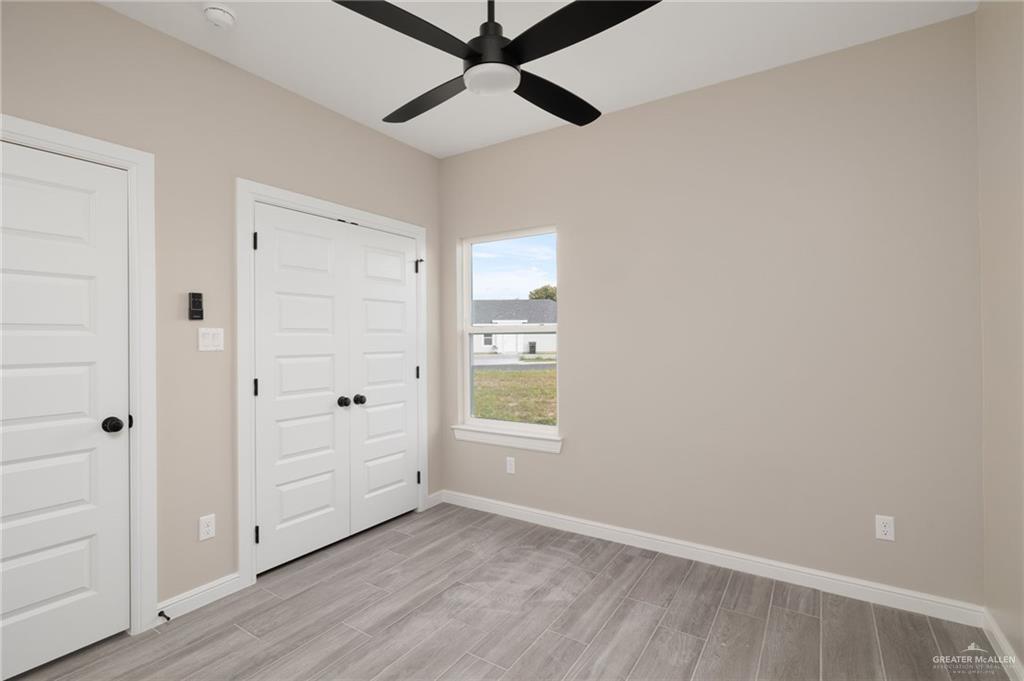 905 Crestview Street Weslaco, TX 78596 - Photo 6 of 10 an empty room with wooden floor cabinet and windows