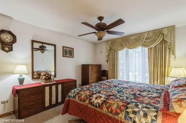 a bedroom with a bed a dresser and a chandelier