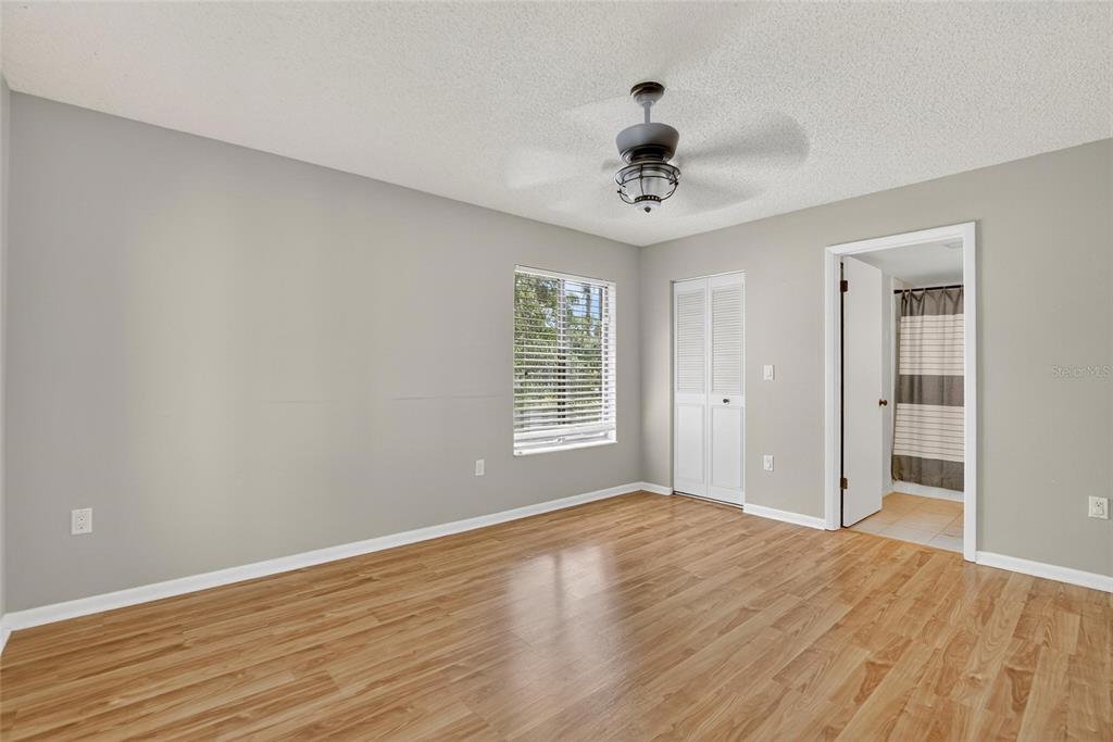 1225 Pine Ridge Circle West, Unit A2 Tarpon Springs, FL 34688 - Photo 23 of 59 a view of an empty room with wooden floor and a ceiling fan