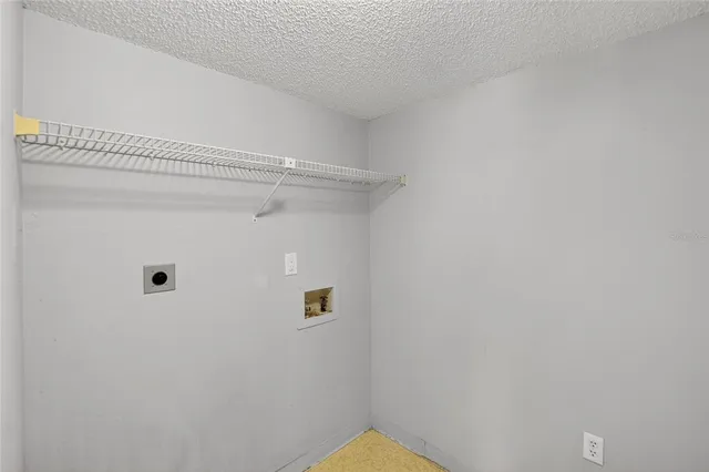 a view of a refrigerator in kitchen and an empty room with wooden floor