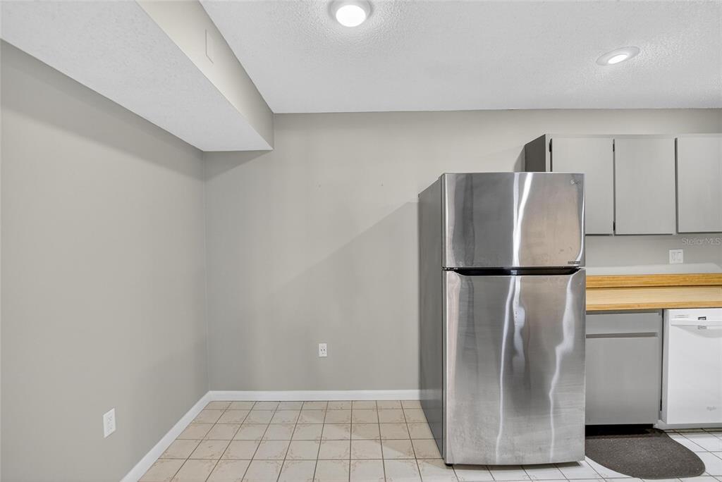 1225 Pine Ridge Circle West, Unit A2 Tarpon Springs, FL 34688 - Photo 43 of 59 a view of a refrigerator in kitchen and an empty room with wooden floor