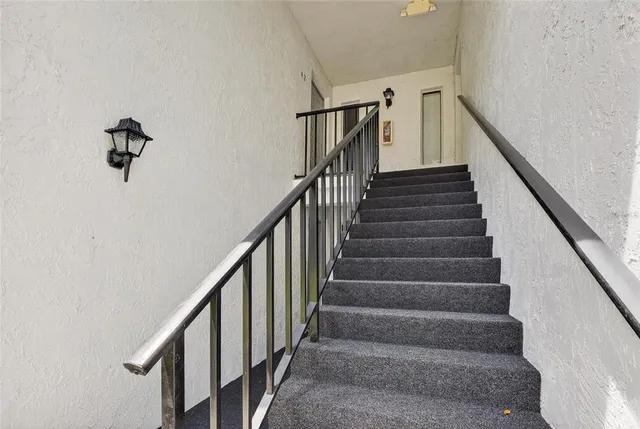 a view of staircase with railing and white walls