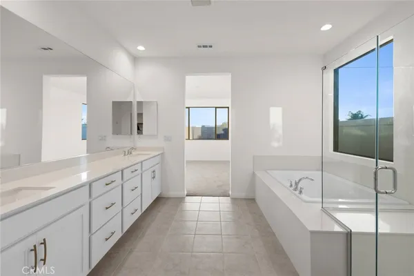 a large white bathroom with a double vanity sink a mirror and a bathtub