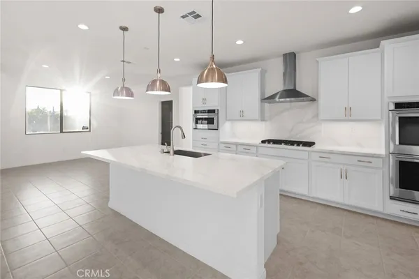 a kitchen with stainless steel appliances kitchen island granite countertop a sink a stove a refrigerator and white cabinets