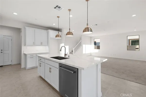 a kitchen with a sink a stove a refrigerator and white cabinets